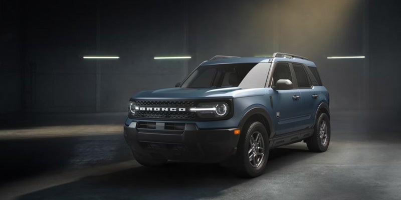 Blue Ford Bronco Sport SUV parked in a dimly lit indoor showroom, highlighting the vehicle's rugged design